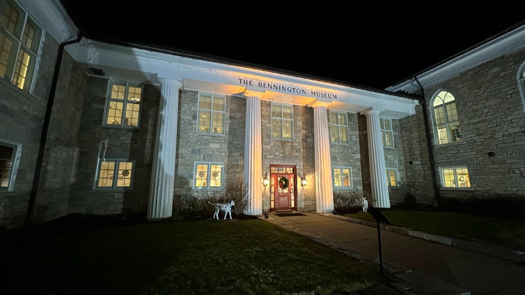 The Bennington Museum entrance at night, columns washed with warm light.