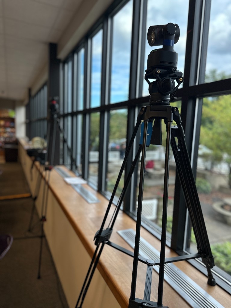 Two 4K PTZ cameras on tripods along the cafeteria windows at the Mack Molding Global Town Hall.